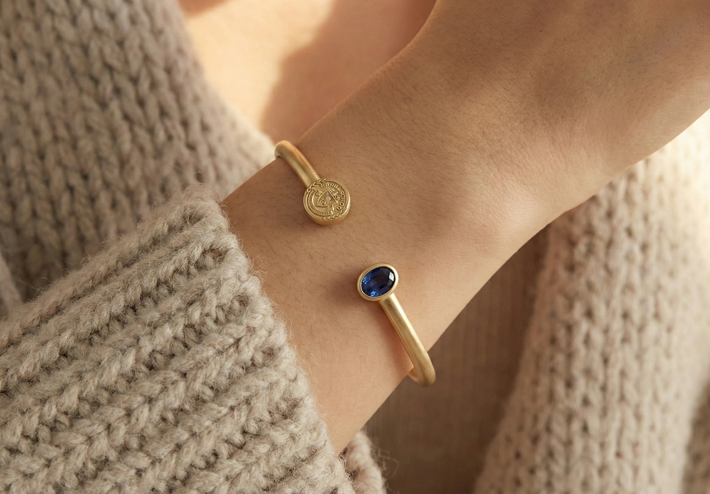 Crest and sapphire open cuff bracelet worn on the wrist