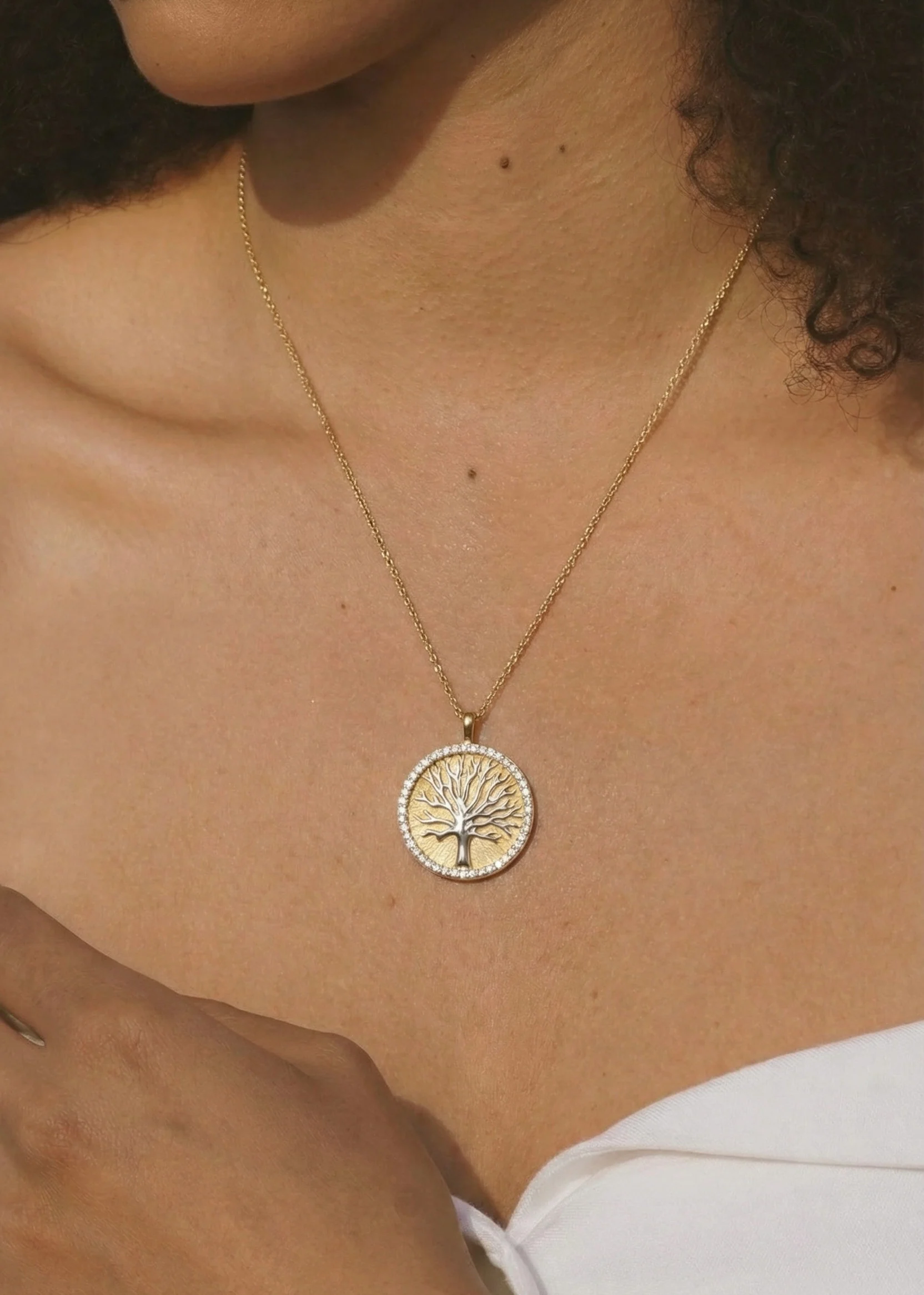 Woman wearing a gold and diamond tree medallion necklace